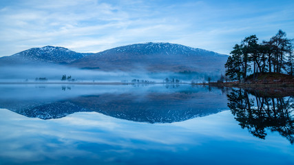 landscape view of scotland and loch tulla at blue hour in winter with calm waters and fog 