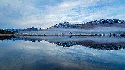 landscape view of scotland and loch tulla at blue hour in winter with calm waters and fog 