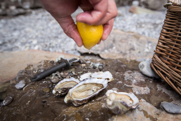 hand sqeezing lemon on a fresh open oyster