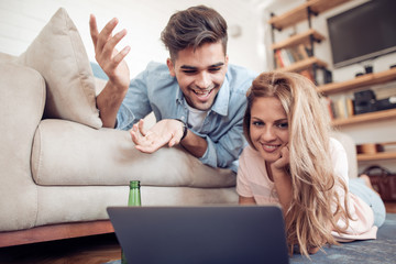 Fototapeta premium Beautiful young couple in casual clothes is using a laptop.