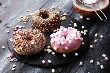 assorted donuts with chocolate frosted, pink glazed and sprinkles donuts.
