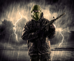 Dangerous armed terrorist with mask and gun in a thunderstorm with lightning