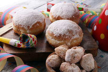 German donuts with jam and icing sugar. Carnival powdered sugar raised donuts with paper streamers.