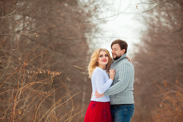 beautiful young couple in love, in light sweaters, walking in the park in cold weather