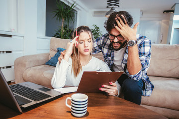 Woman and man doing paperwork together, paying taxes online on notebook pc