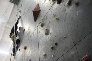 Climbing rocks on climbing wall. Fitness, extreme sport, bouldering, people and healthy lifestyle concept - people exercising at indoor climbing gym. Close-up image