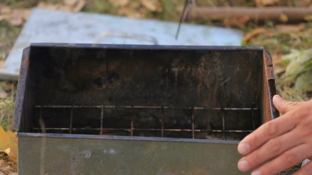the man hunter puts the shavings of the trees in the smokehouse. Bonfire on the river bank. clouse-up