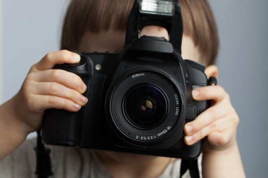 Beautiful child in with professional camera. Little boy with long blond hair photographing in the Studio