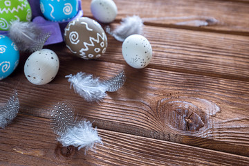 Painted Easter eggs with feathers and a branch of sakura on a dark wooden background