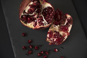Ripe red pomegranate on a black background. Healthy food, diet concept