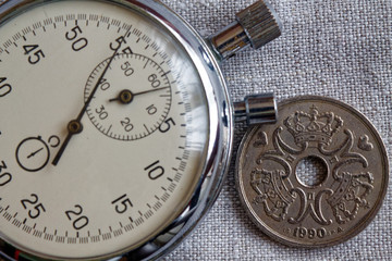 Denmark coin with a denomination of five crown (krone) (back side) and stopwatch on flax canvas backdrop - business background