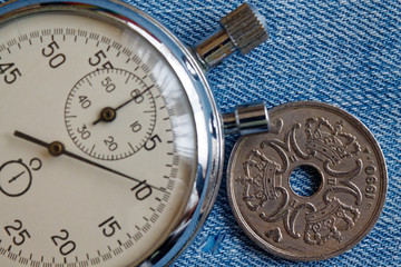 Obraz na płótnie Canvas Denmark coin with a denomination of five crown (krone) (back side) and stopwatch on worn blue jeans backdrop - business background