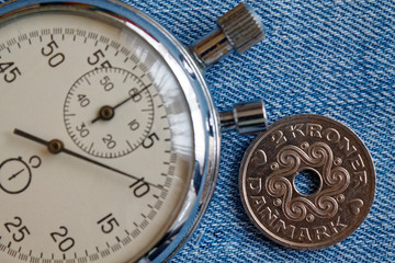 Denmark coin with a denomination of 2 krone (crown) and stopwatch on old blue jenas backdrop - business background