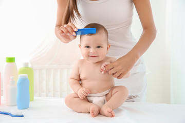 Mother combing cute baby after bathing at home