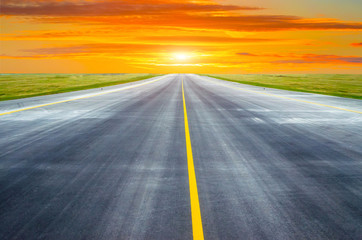 Runway and road goes into the horizon at sunset dawn.