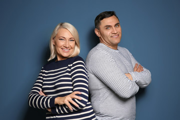 Cute middle-aged couple on color background