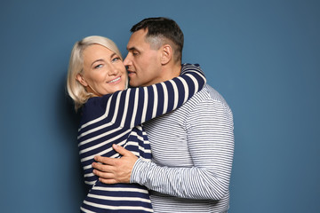 Cute middle-aged couple on color background