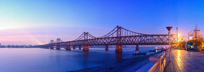 Yalu River Bridge at morning. In the distance is North Korea. Located in Dandong, Liaoning, China.