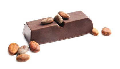 Piece of chocolate and cocoa beans on white background
