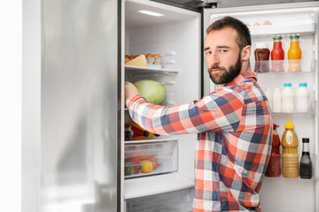 Fototapeta na wymiar Handsome man choosing food in refrigerator at home