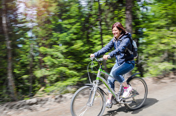 Woman Riding a Bicycle on a Mountain Road on a Sunny Spring Day. Blurred Motion.