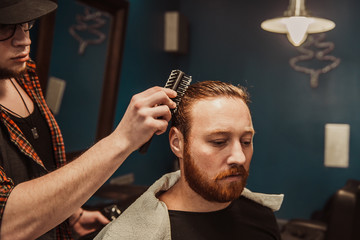 A man visits a hairdresser. The hairdresser does a hairstyle to a man. Hipster in the hairdresser