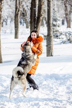 Girl playing with a dog in the park in winter.