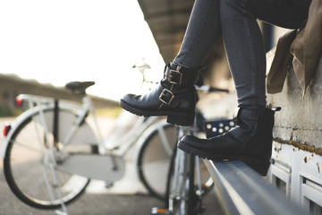 Girl is sitting in a vintage location with bicycles in the backround.