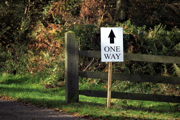 Wooden gate on a road through forest or woodland, with a sign saying 