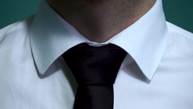 Caucasian man with white shirt fixing his black tie