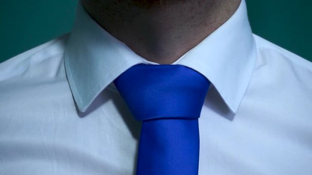 Caucasian man with white shirt fixing his blue tie