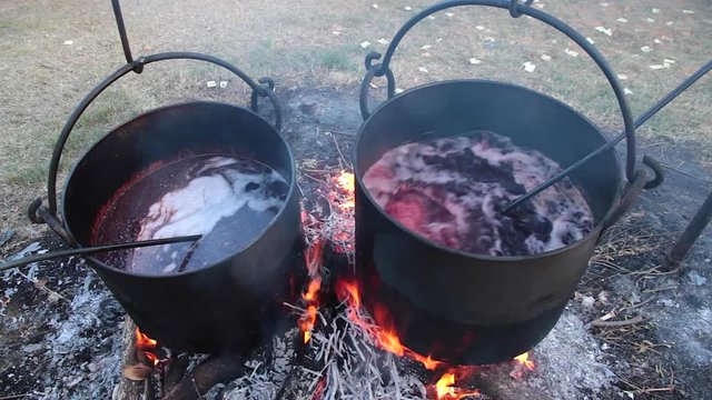Dos grandes ollas o cacerolas de cobre colgadas al fuego, cociendo chorizo en vino