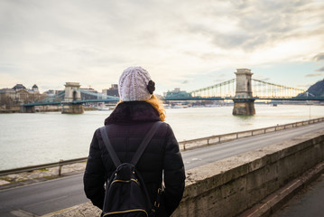 Young woman is looking at the Chain bridge from Danube riverbank by the road in Budapest, Hungary.