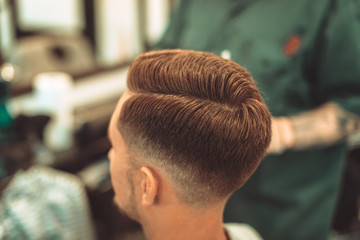 Barber styling beard with trimmer at barbershop, closeup. Barbershop for men