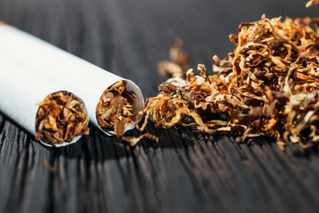Homemade cigarettes and tobacco on the brown wooden table, close up with copy space
