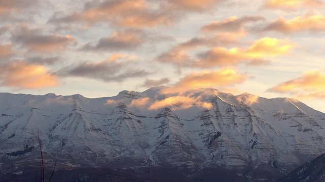 Clouds passing by mountain peak during sunrise over Timpanogos Mountain in Utah.