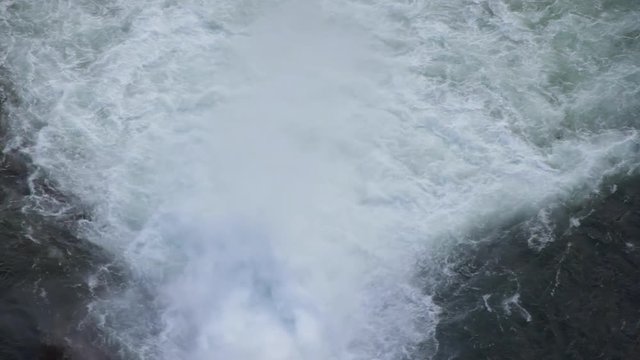 Gran chorro de agua saliendo del dique de una presa visto desde arriba