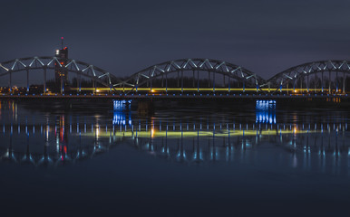 Picturesque view on the modern architecture of Riga panorama over the river with blue sky in background. Lights creating reflections in river.