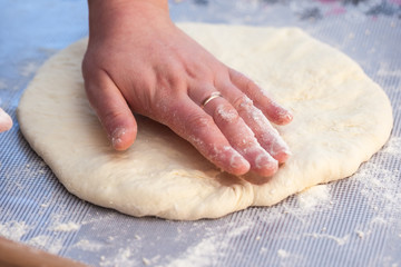 Baker hands preparing khachapuri on kitchen table. View on cook making traditional georgian treat with raw dough