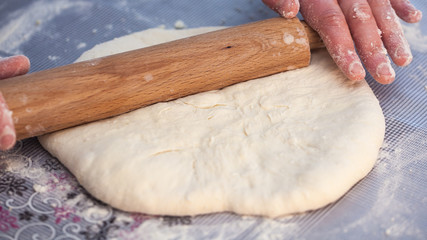 Baker hands preparing khachapuri on kitchen table. View on cook making traditional georgian treat with raw dough