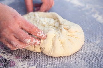 Baker hands preparing khachapuri on kitchen table. View on cook making traditional georgian treat with raw dough