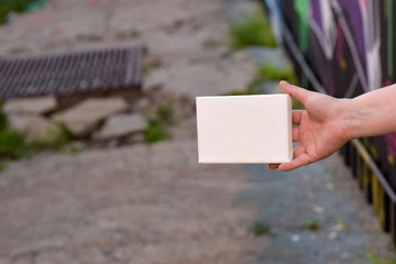 Female hand with tiny canvas in front of urban background