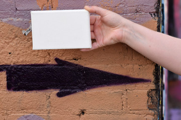 Female hand with tiny canvas in front of urban background