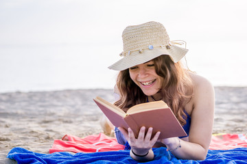 happy girl smiling reading book on the sunny beach