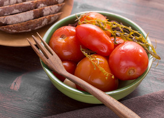 Pickled tomatoes and wooden fork in bowl. Russian cuisine