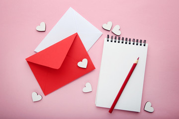 White hearts with envelopes, notebook and pencil on pink background