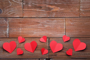 Red paper hearts on brown wooden table