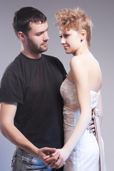 Relationships Ideas and Concepts. Playful Caucasian Couple Embracing Together. Blond Female Wearing Tailored Wedding Dress. Against Gray.