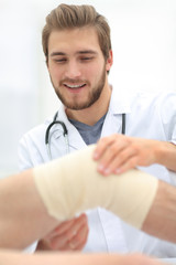 traumatologist examining the bandage on his knee.