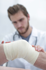 traumatologist examining the bandage on his knee.